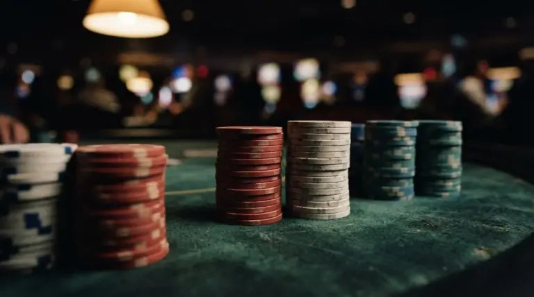 Several stacks of colorful casino chips rest on a green felt gaming table in a dimly lit room