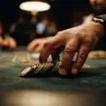 A single hand swiftly sweeps a small, neat stack of casino chips from dark green felt