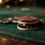 A stack of multicolored casino poker chips rests on a green felt table surface