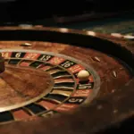 A close-up, low-angle detail of a roulette wheel, emphasizing the numbered pockets and ball track
